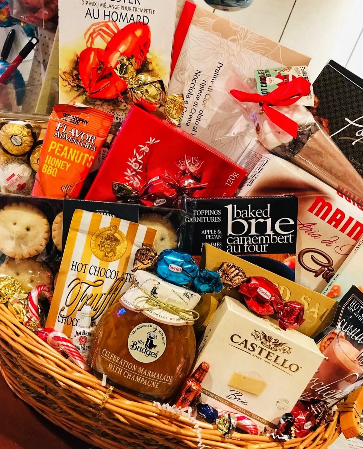 Wicker gift basket filled with gourmet cheeses, marmalade, snacks, and a cookbook.