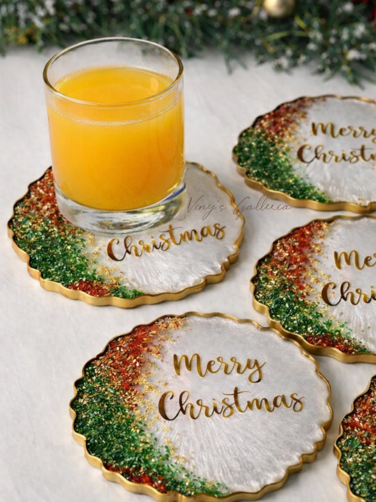 Resin Christmas coasters with gold edges and glitter holding a glass of juice.