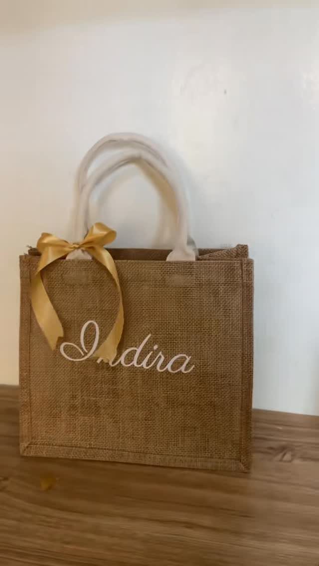 Burlap tote bag with white handles, gold bow, and personalized name Indira.