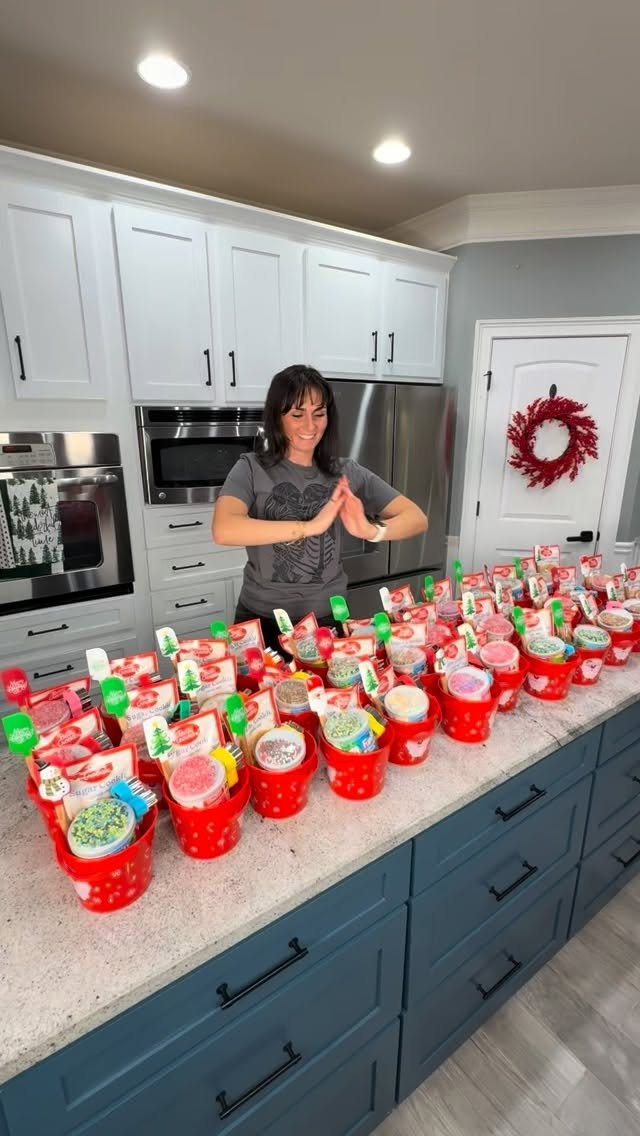 Woman standing behind a kitchen counter filled with red gift buckets for coworkers