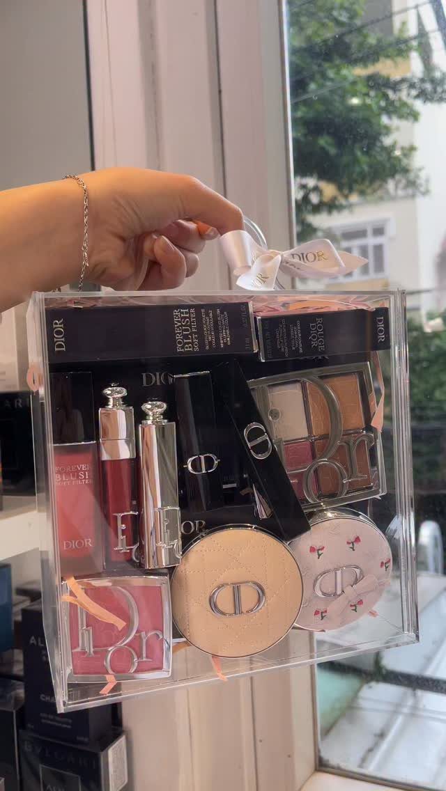 Dior cosmetics gift set in a clear acrylic box with a white ribbon.