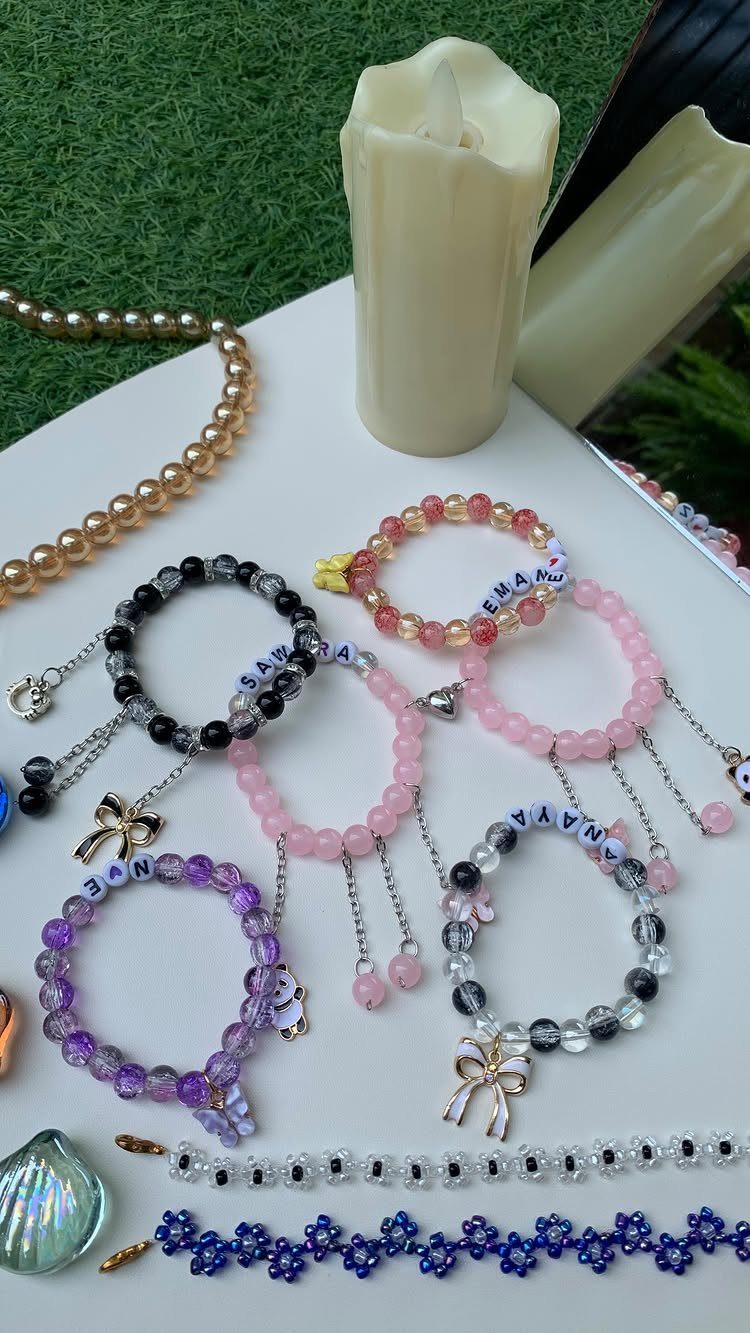 Beaded bracelets with letter beads and charms arranged on a white surface.