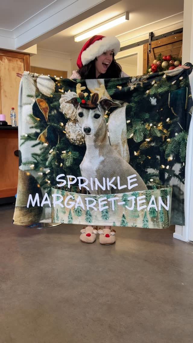Woman holding a personalized blanket featuring a dog and Christmas tree background.