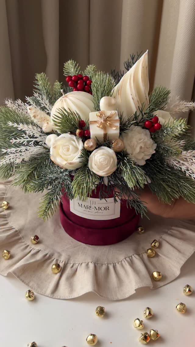 Festive floral arrangement in a burgundy velvet box with white roses and pine.