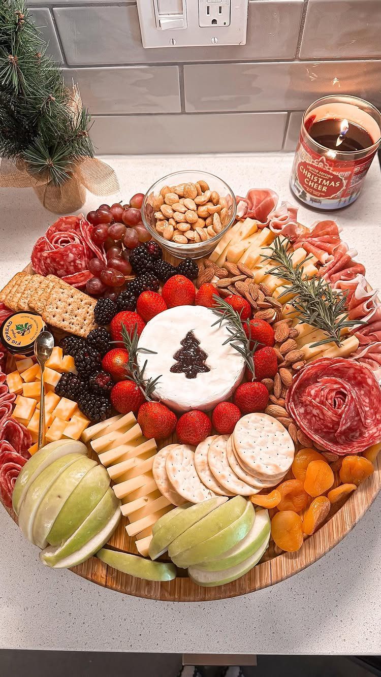 Round wooden charcuterie board with meats, cheeses, and fruits for a Christmas party.
