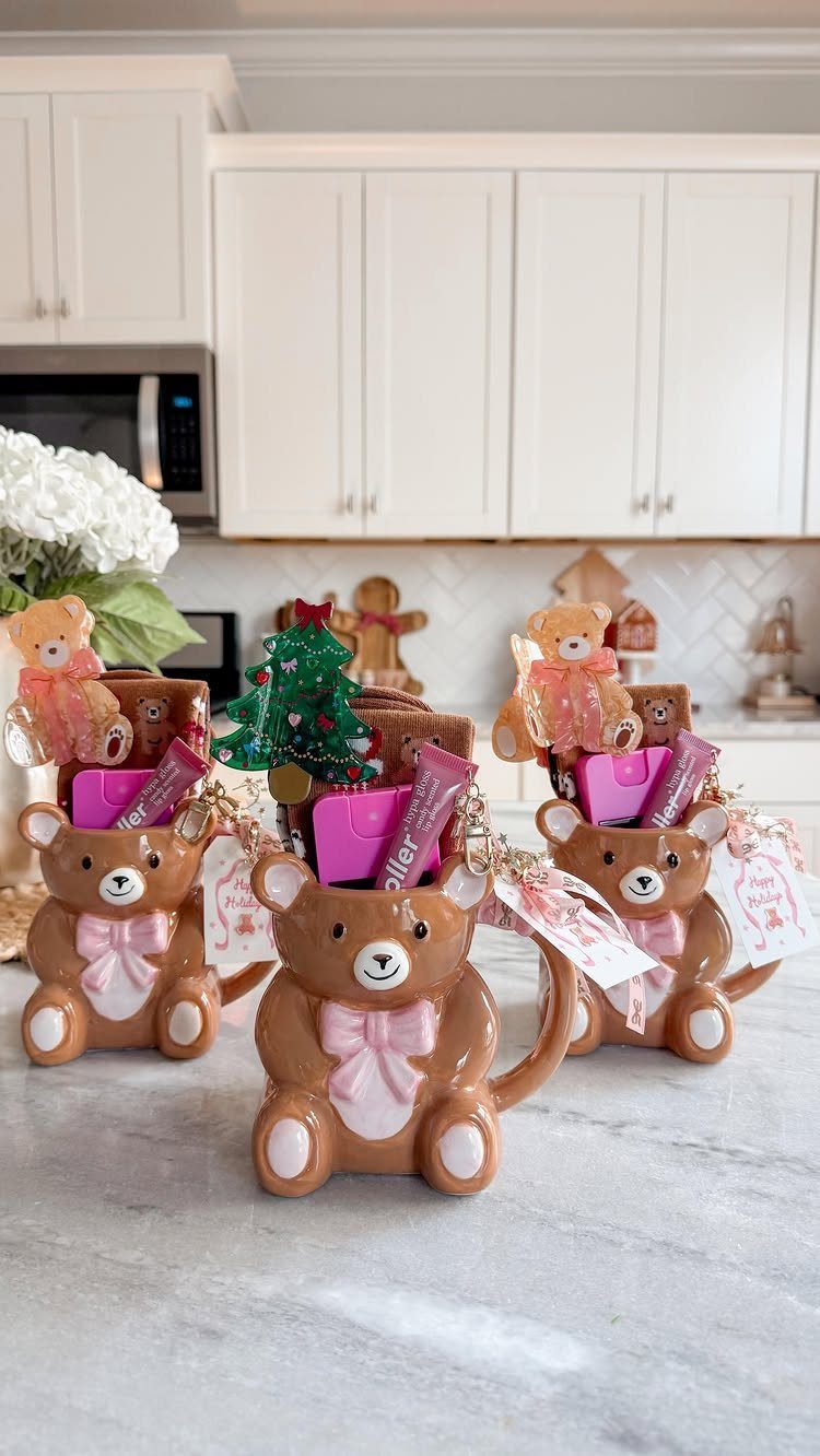Bear-shaped ceramic mugs filled with small Christmas gifts on a white marble counter.