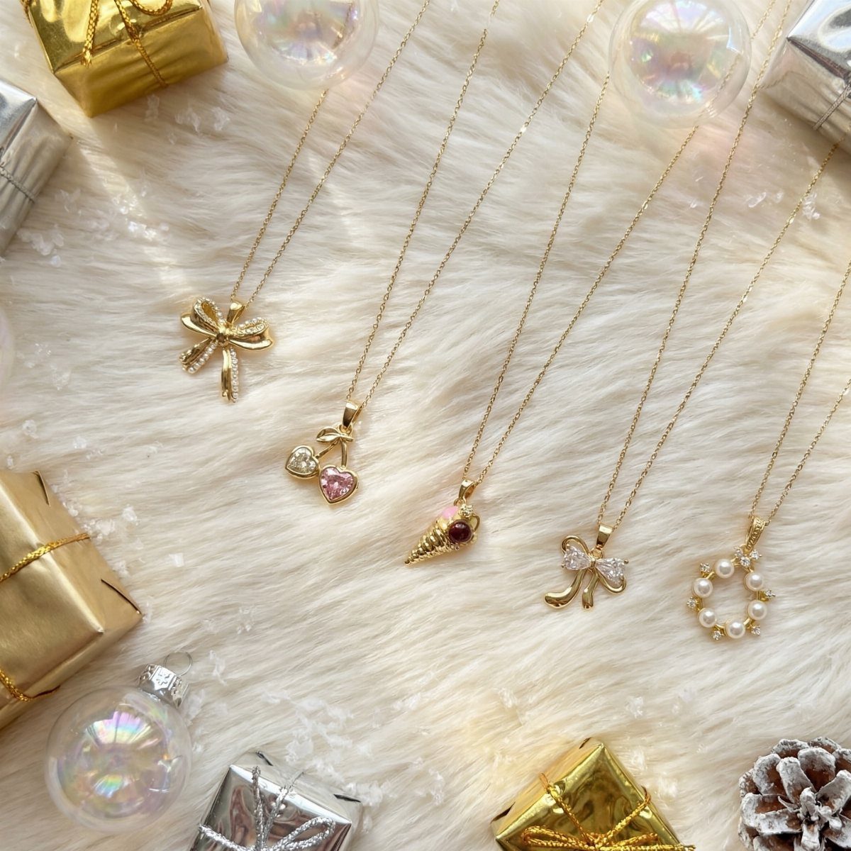 Five gold necklaces with various pendants on white fur with Christmas gift boxes.