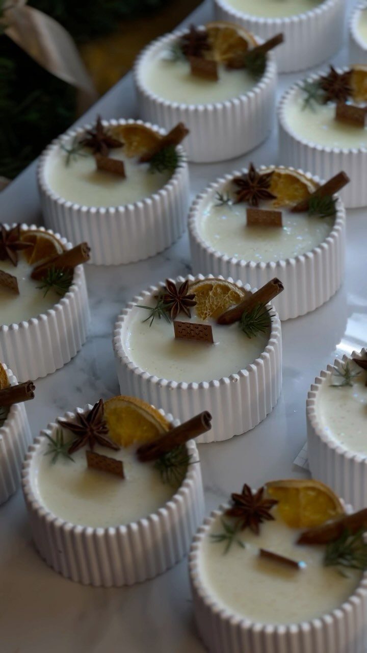 White ribbed containers with creamy filling topped with cinnamon, star anise, and orange slices.