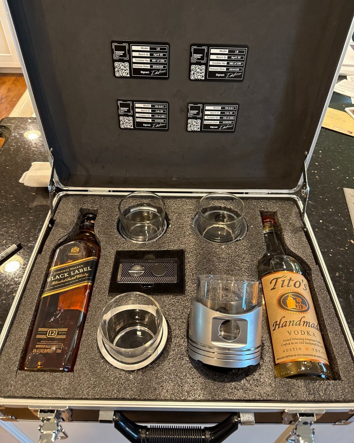 Alcohol gift set in a silver briefcase with whiskey, vodka, and glasses.