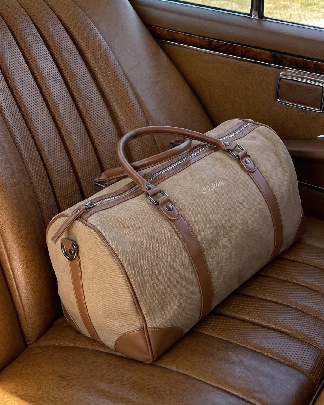 Tan leather travel duffel bag sitting on a brown vintage car seat