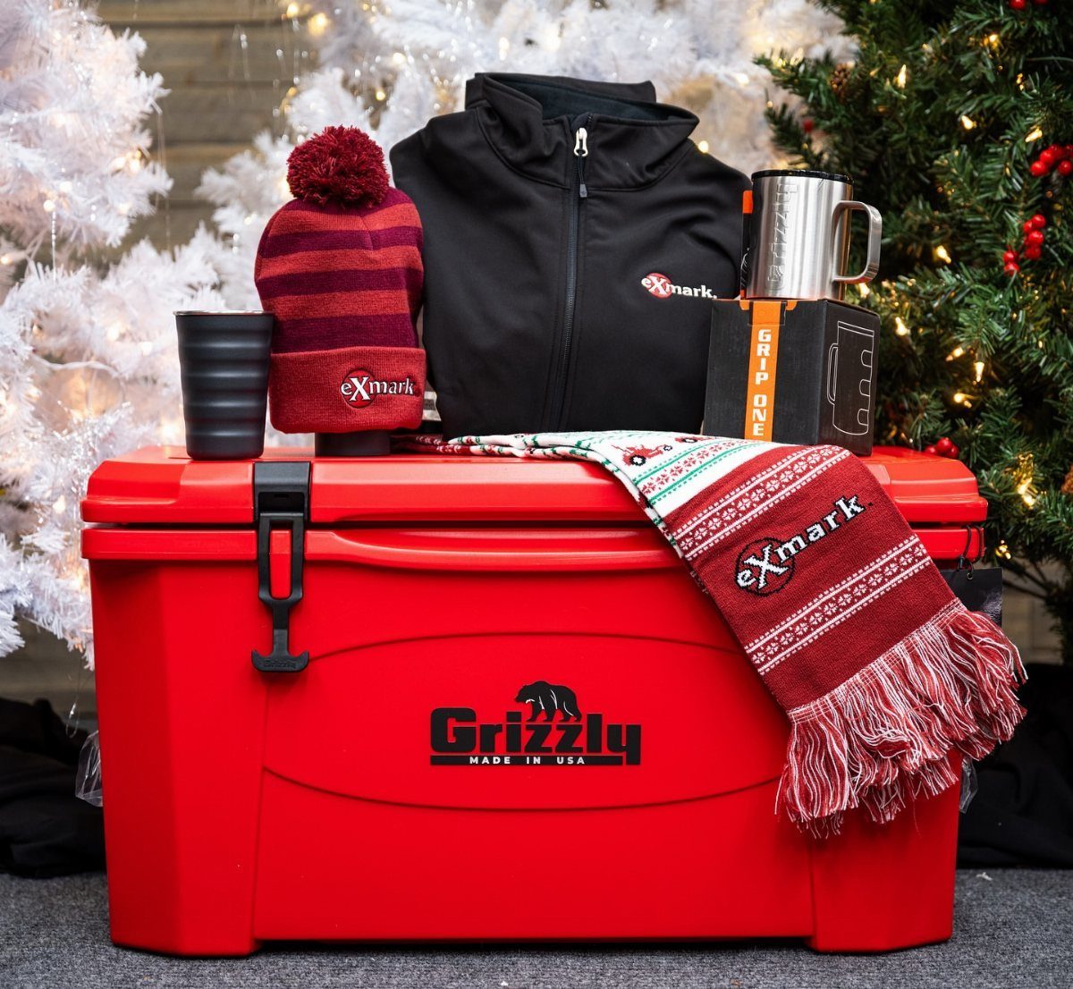 Red Grizzly cooler filled with winter clothing and gear near Christmas trees.