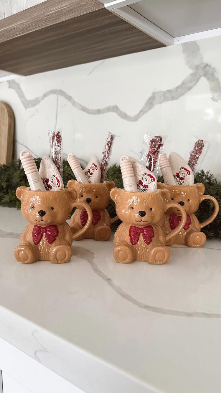 Four bear-shaped ceramic mugs with red bows and candy canes on marble counter
