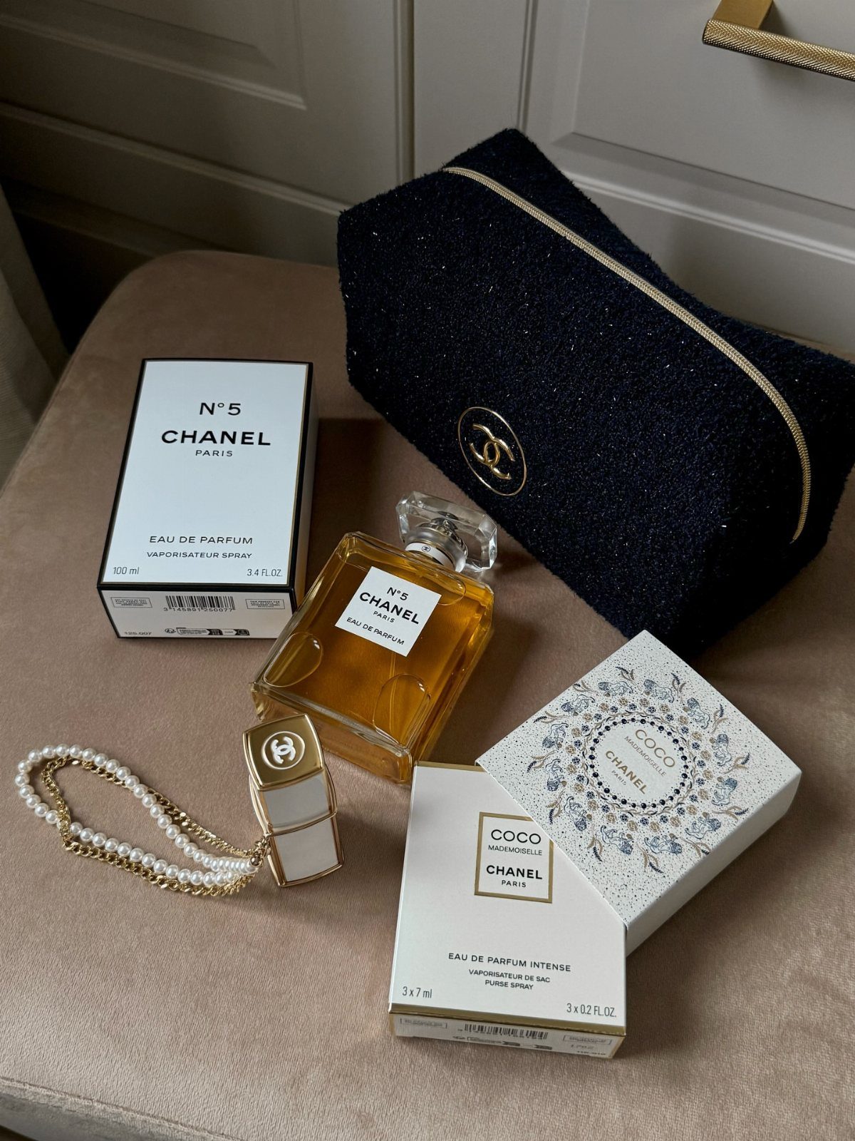 Chanel No. 5 perfume bottle and box with a black glittery makeup bag.