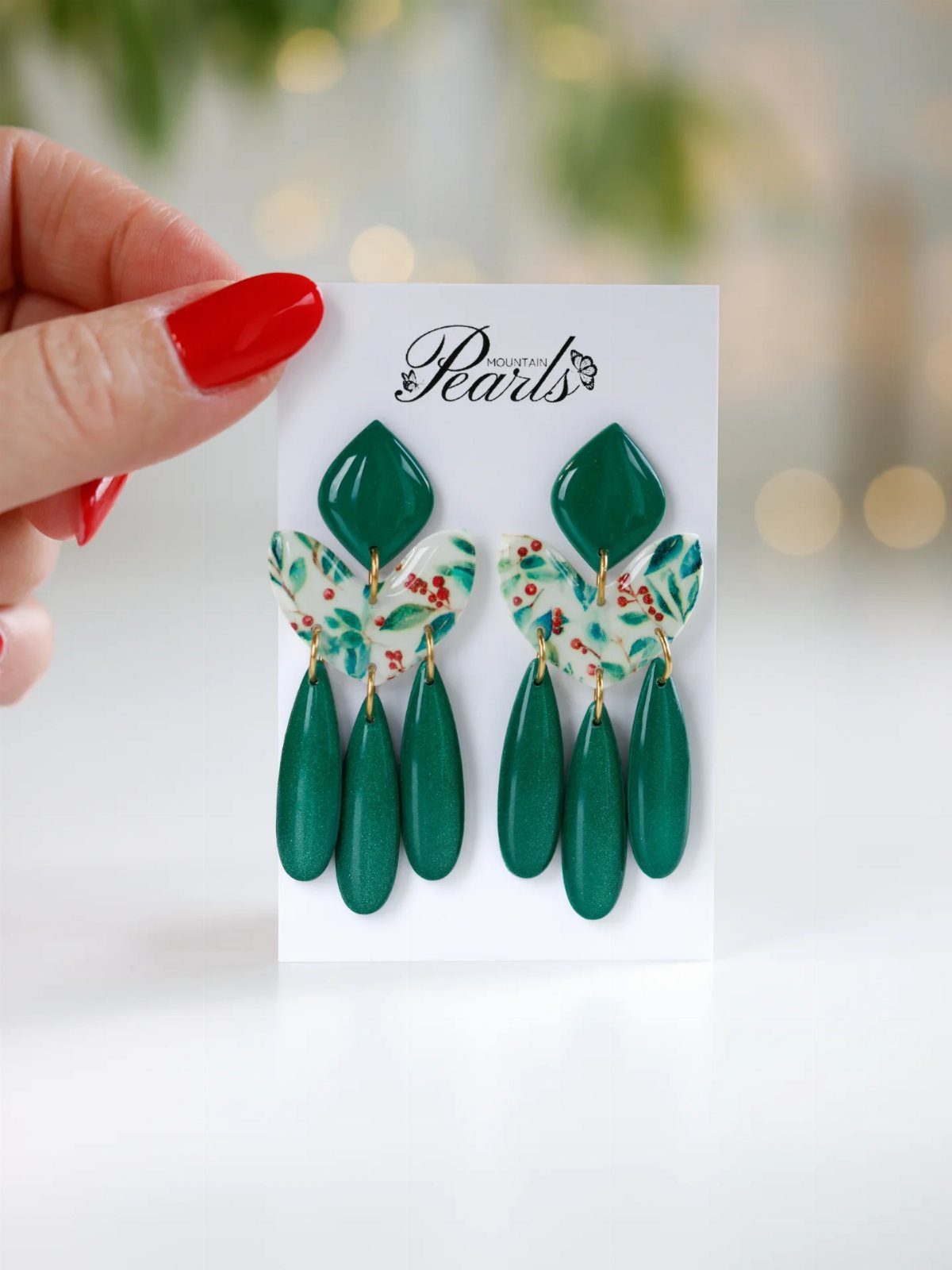 Green statement earrings with floral details displayed on a white jewelry card.