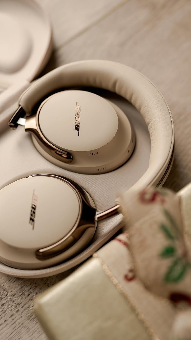 Beige Bose headphones in a case next to a wrapped Christmas gift.