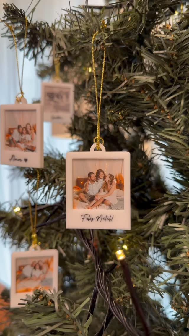 Polaroid photo ornaments hanging on a green Christmas tree with warm fairy lights.