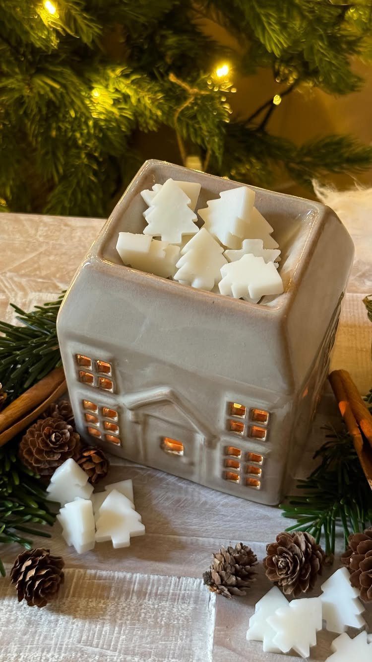 House-shaped ceramic wax warmer with white tree wax melts and Christmas decorations.