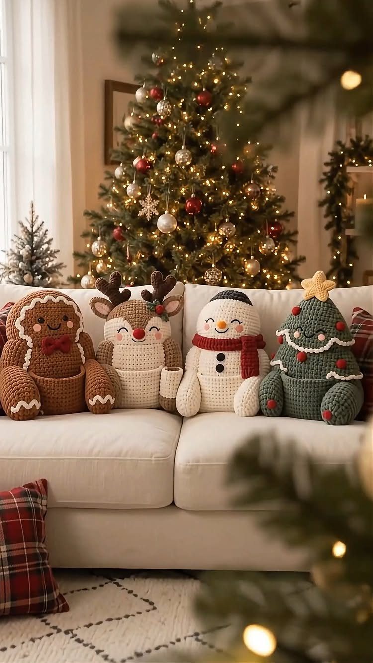 Crocheted Christmas plushies on a white sofa in front of a lit tree.