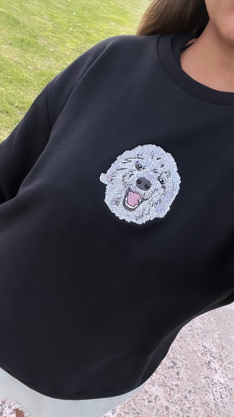 Black sweatshirt featuring a small white embroidered dog face on the chest.