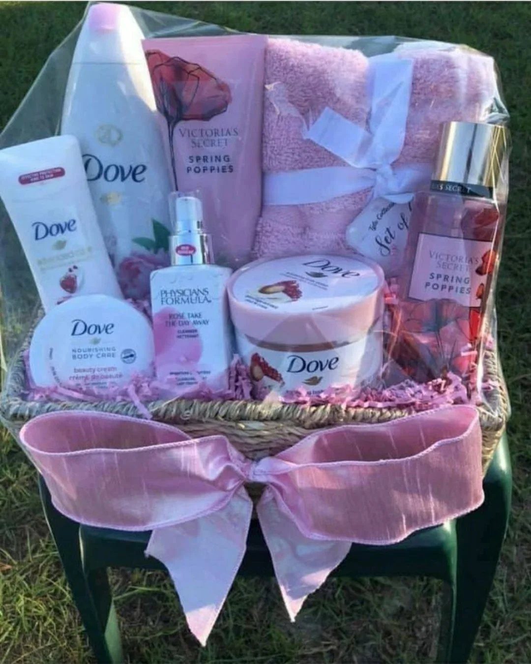 Wicker gift basket filled with pink beauty products and a pink towel.