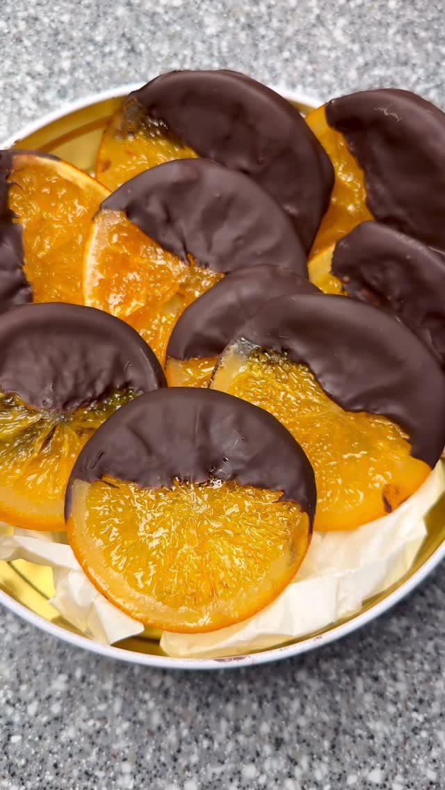 Chocolate dipped dried orange slices arranged in a small gold tin container.