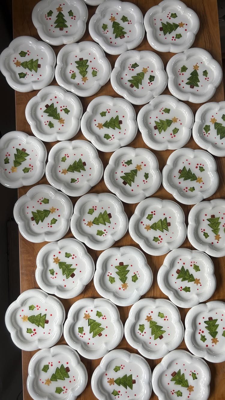 Small white scalloped clay bowls with painted Christmas trees on a wooden table