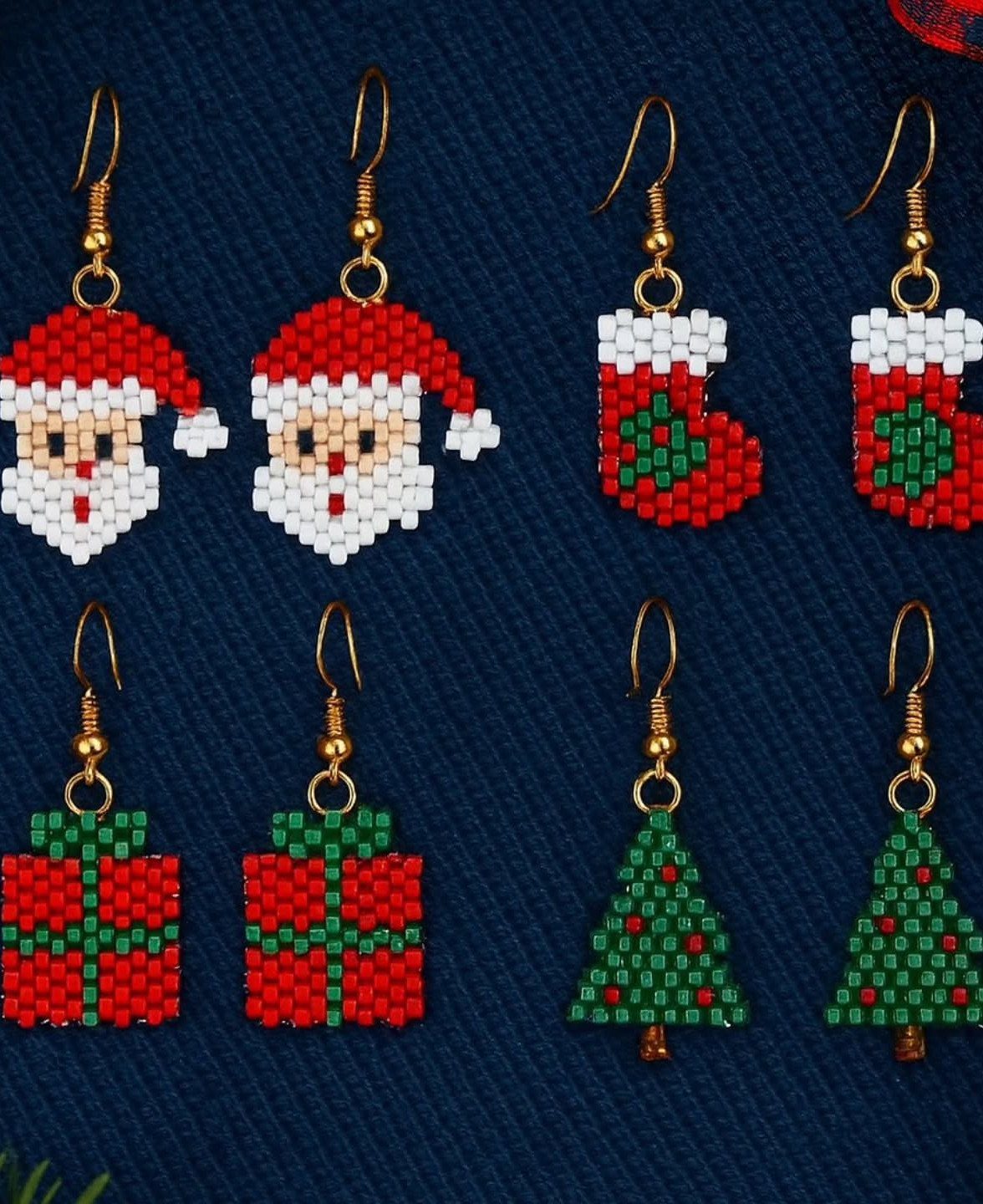 Beaded Christmas earrings featuring Santa, stockings, gifts, and trees on blue fabric.