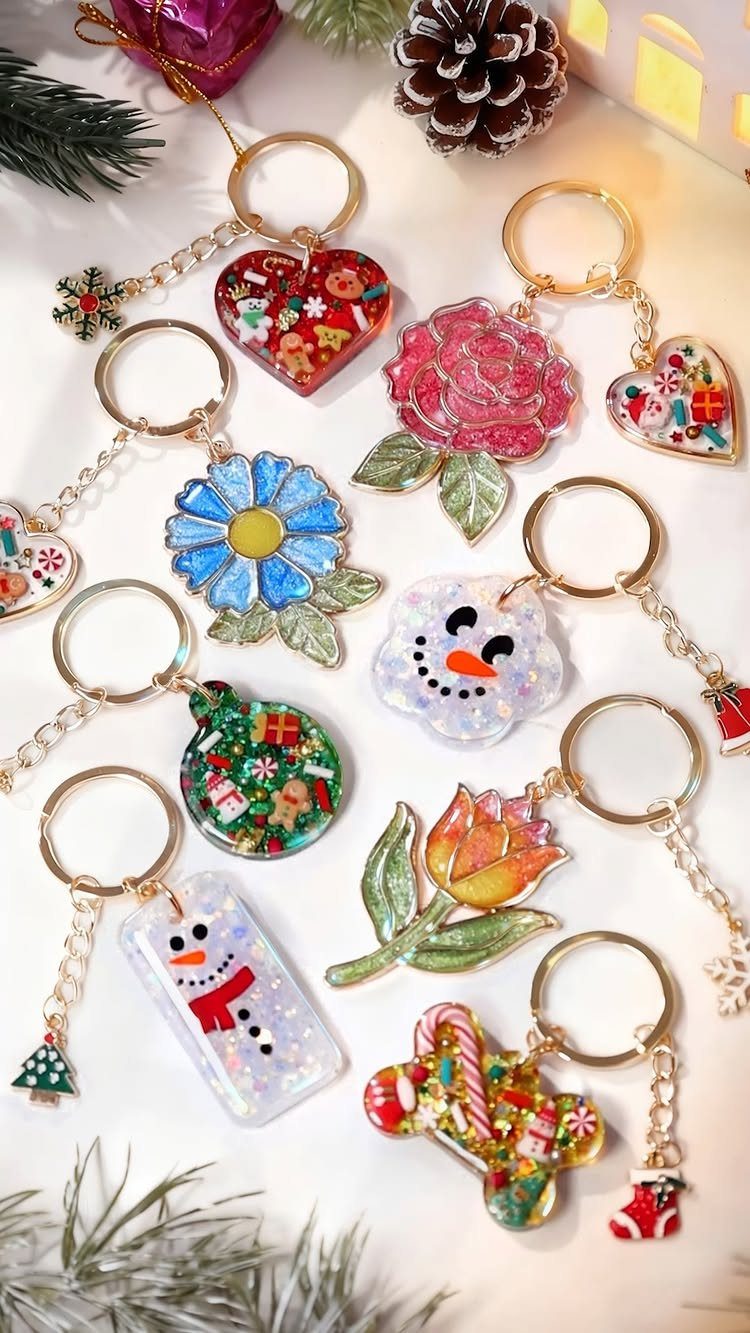 Colorful resin keychains in festive shapes scattered on a white surface with pinecones.