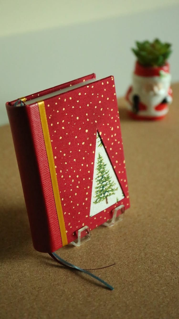 Red handmade notebook with a Christmas tree cutout and a yellow ribbon.