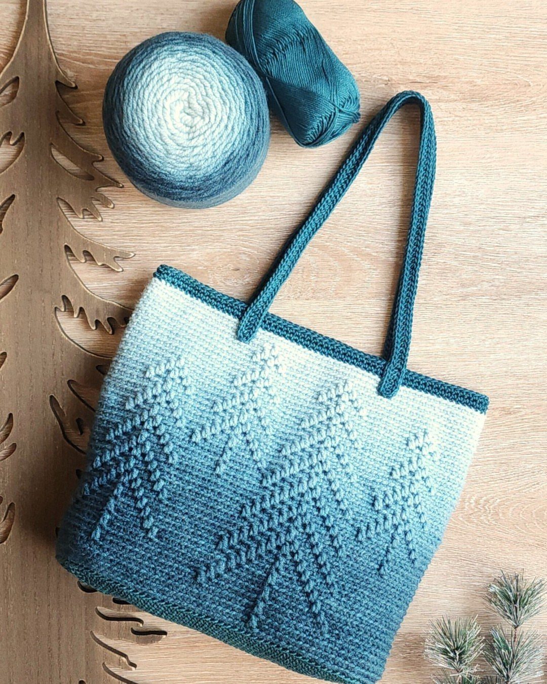 Blue and white gradient crocheted tote bag with yarn on wooden background