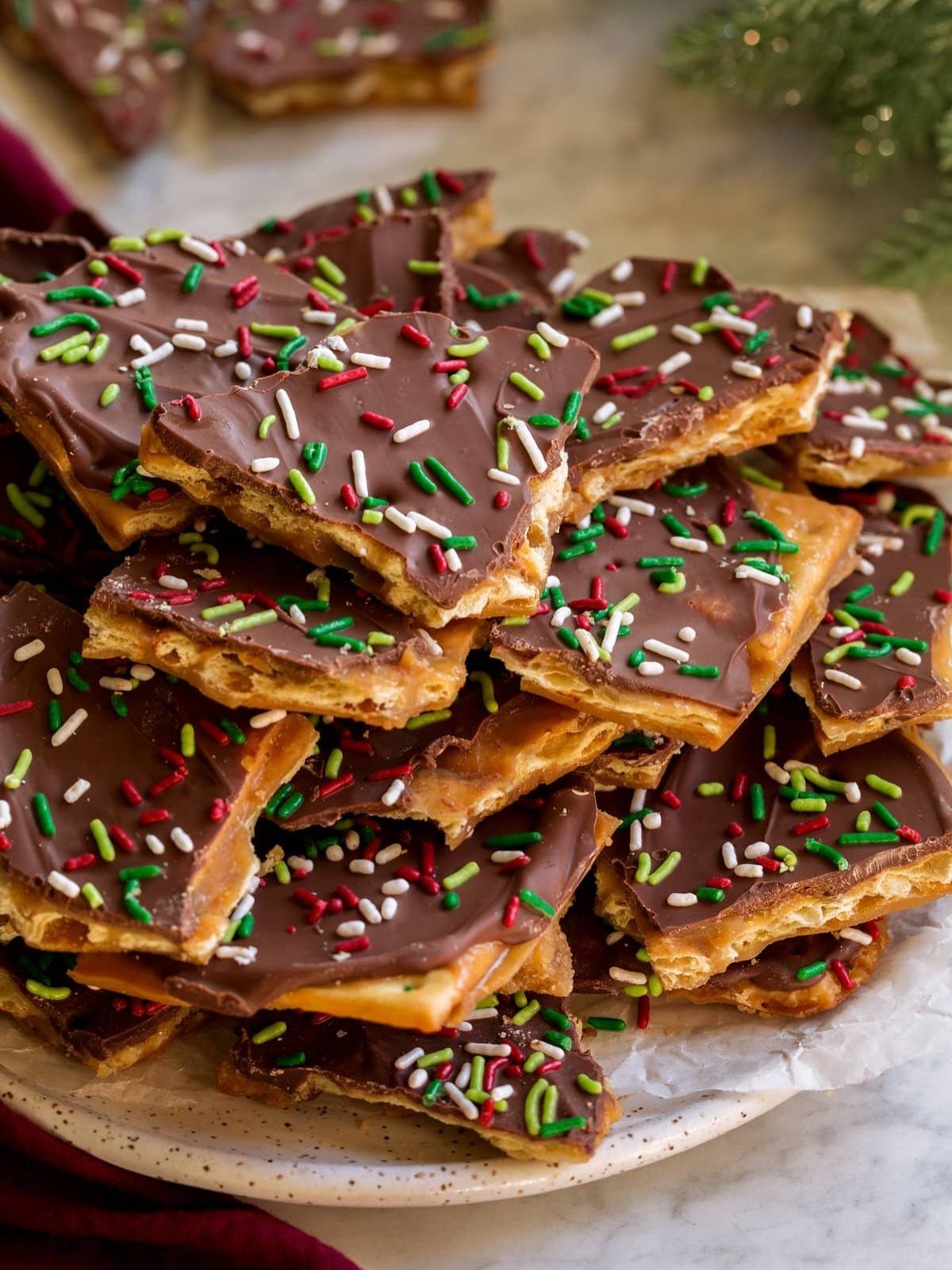 Chocolate pretzel bark with red, green, and white sprinkles on a white plate