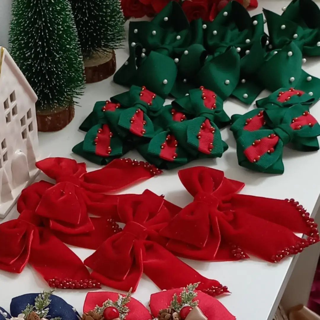 Red and green velvet hair bows with pearls and beads near Christmas decorations.