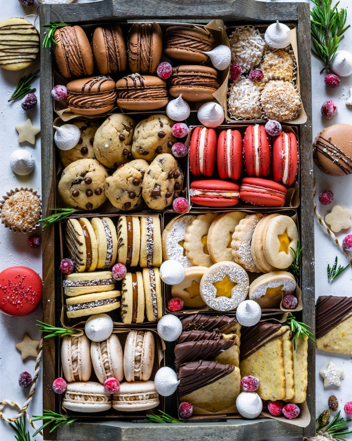 Assorted homemade cookies and macarons arranged in a rustic wooden gift tray.