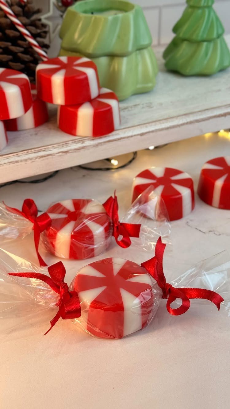 Peppermint-swirl round soaps wrapped in cellophane with red ribbons for Christmas gifts.