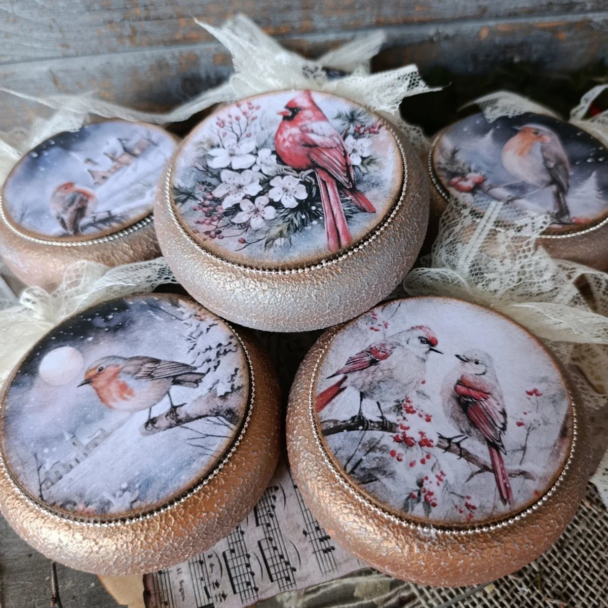 Small bronze decorative boxes with winter bird illustrations on the lids in tulle