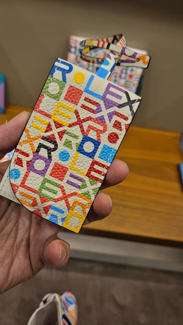 Leather luggage tag with colorful Rolex pattern held in a person's hand