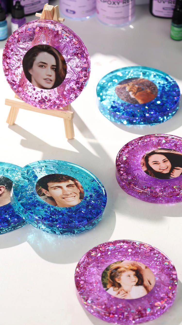 Glittery resin coasters with personalized photos in pink and blue colors.