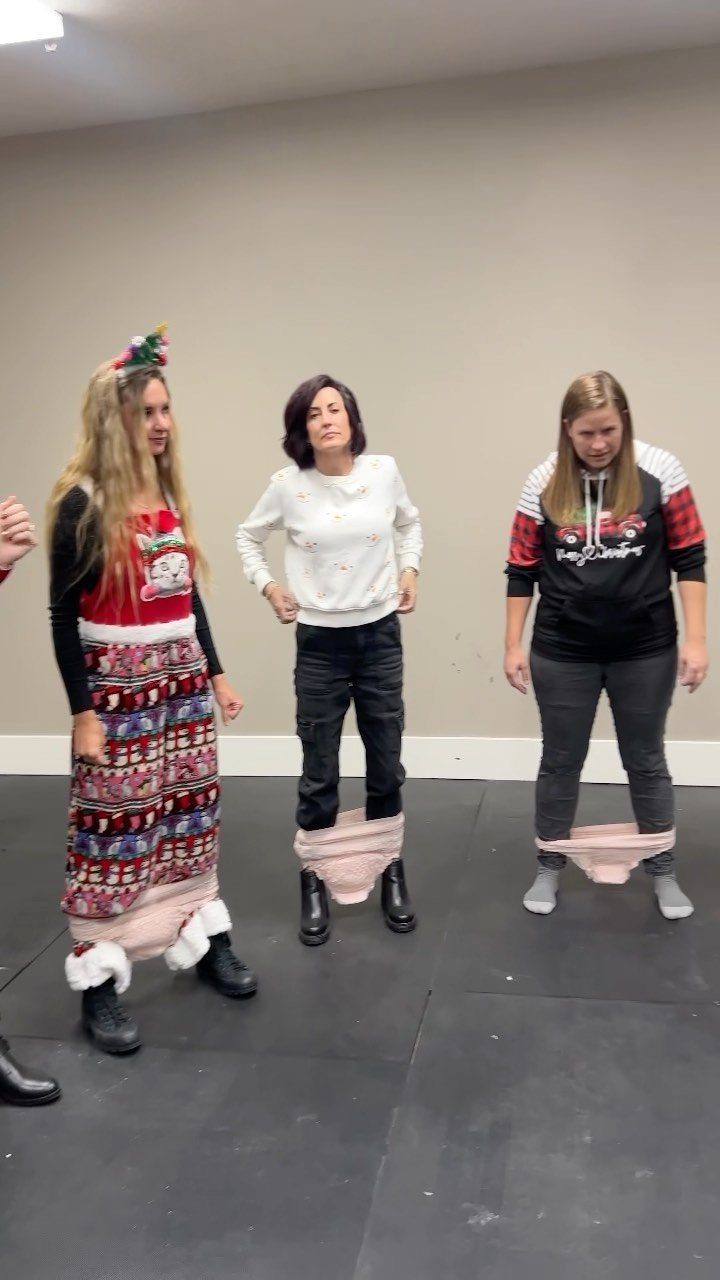 Three women wearing oversized pink underwear over their pants during a holiday party.