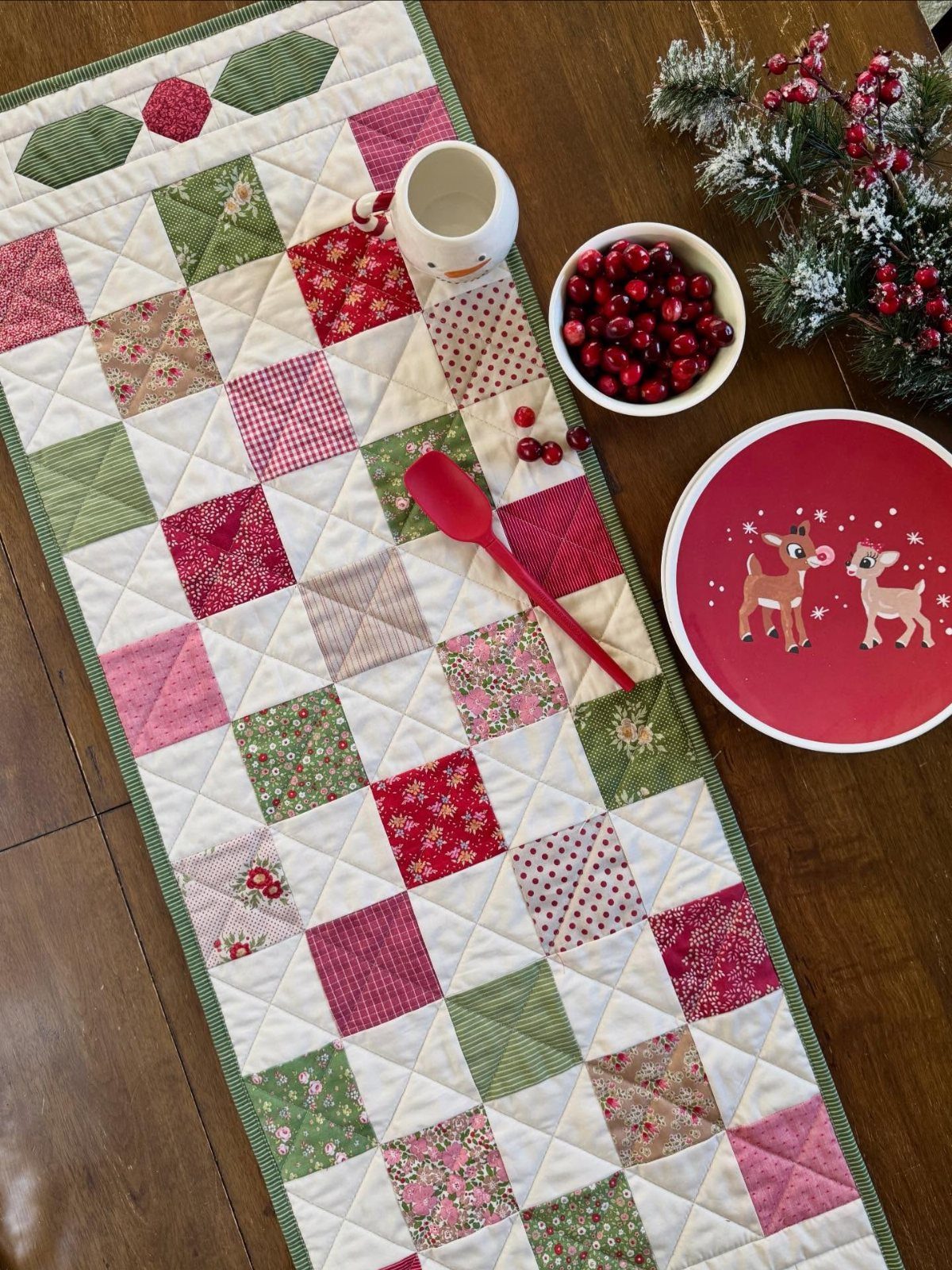 Christmas quilted table runner with red and green patchwork on a wooden table