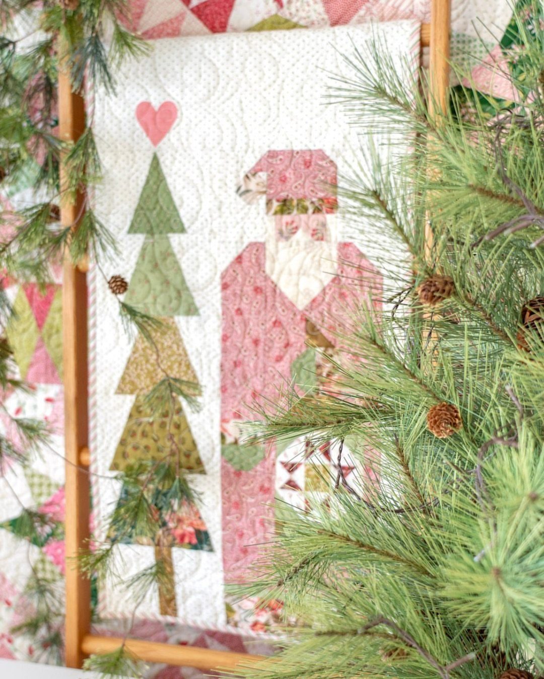 Quilted Christmas table runner with Santa and a tree surrounded by pine branches