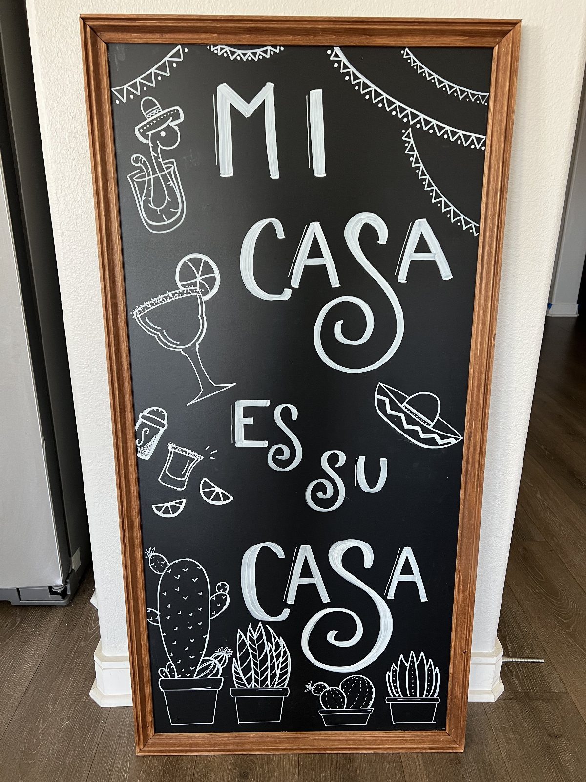 Chalkboard with wooden frame featuring Mi Casa Es Su Casa text and Mexican illustrations