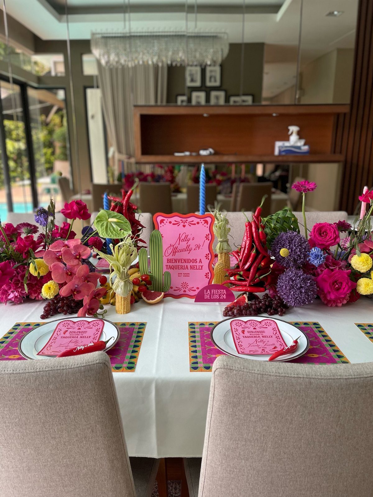 Festive tablescape with colorful disposable placemats, pink napkins, and vibrant floral centerpieces.