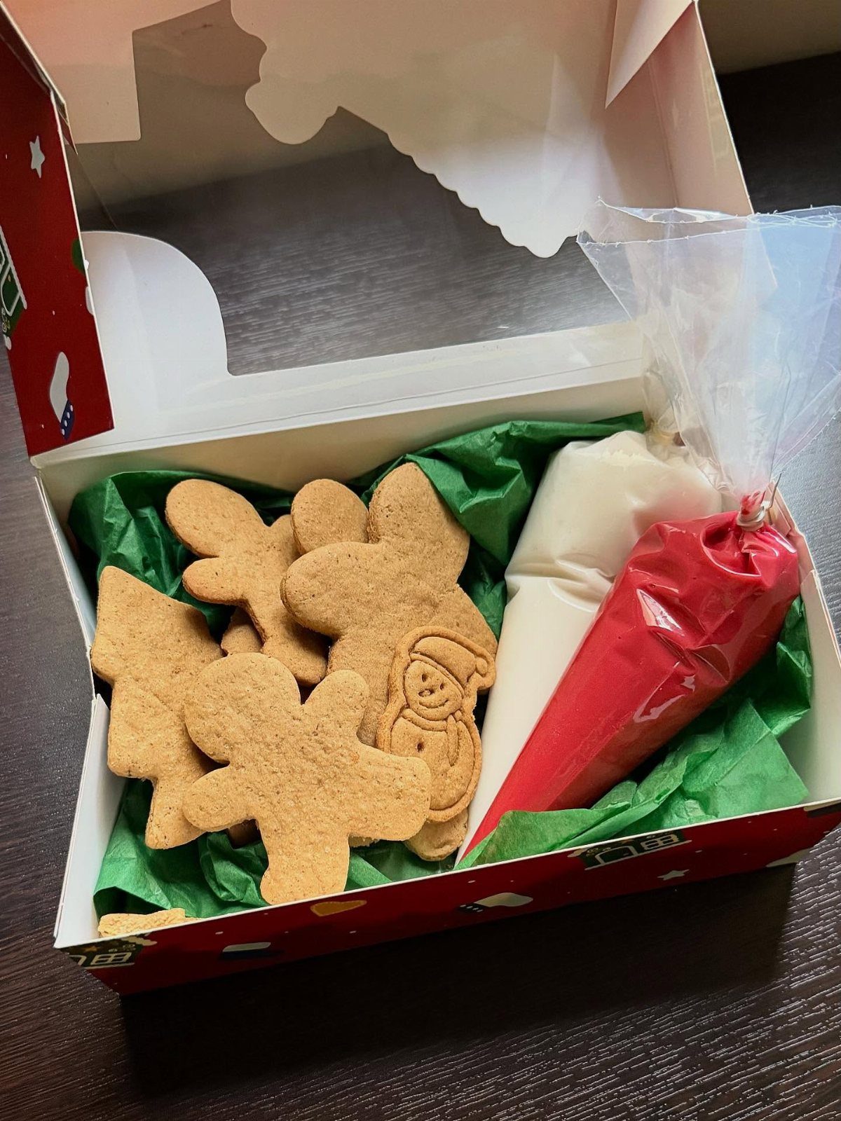 Gingerbread man cookies and frosting piping bags in a festive gift box