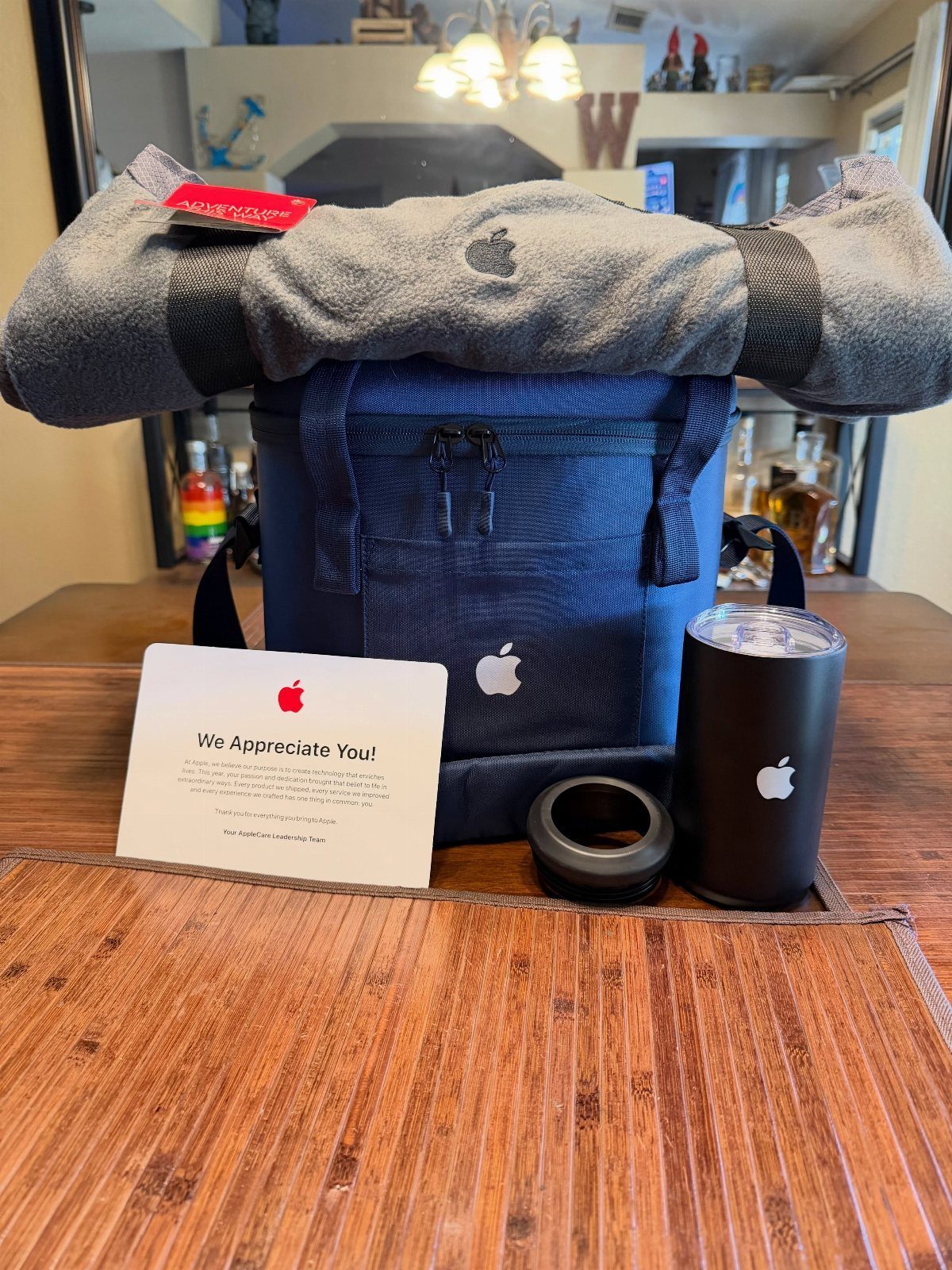 Apple branded gift set with blue cooler, grey blanket, and black tumbler.