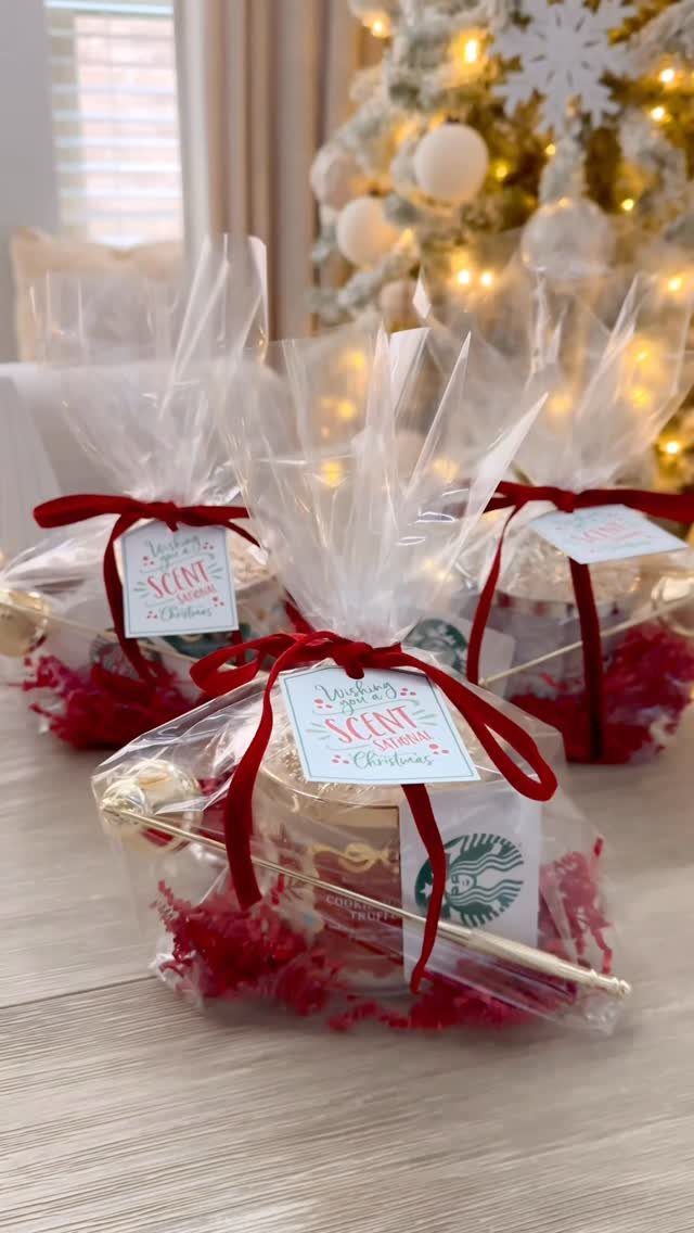 Wrapped candles in cellophane with red ribbons and tags near a Christmas tree