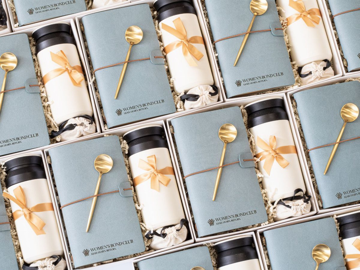Light blue gift boxes containing white containers with gold ribbons and gold spoons.