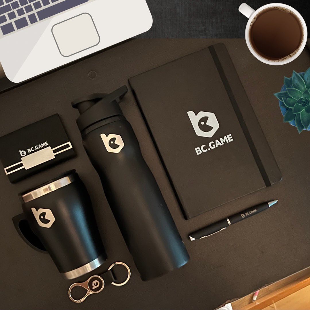 Black branded corporate gift set with notebook, bottle, and tumbler on a desk
