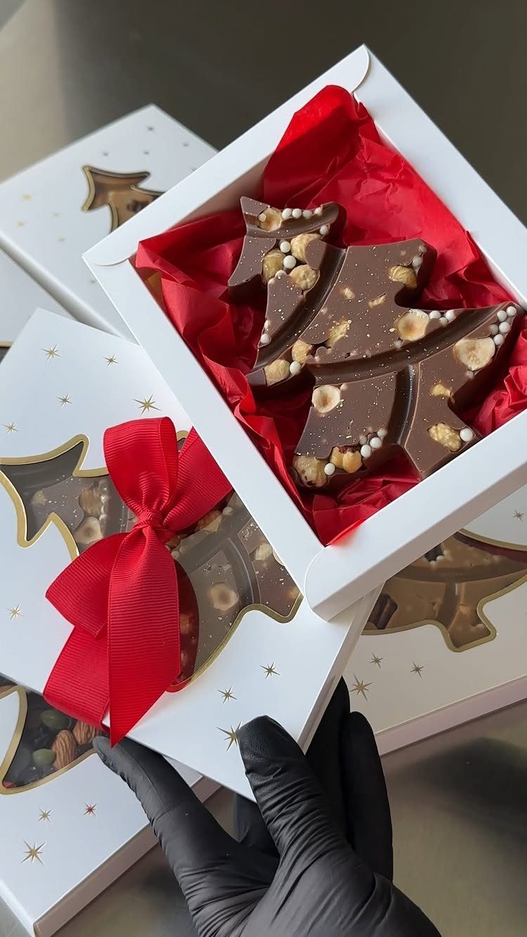 Chocolate Christmas tree with nuts in a white gift box with red ribbon.