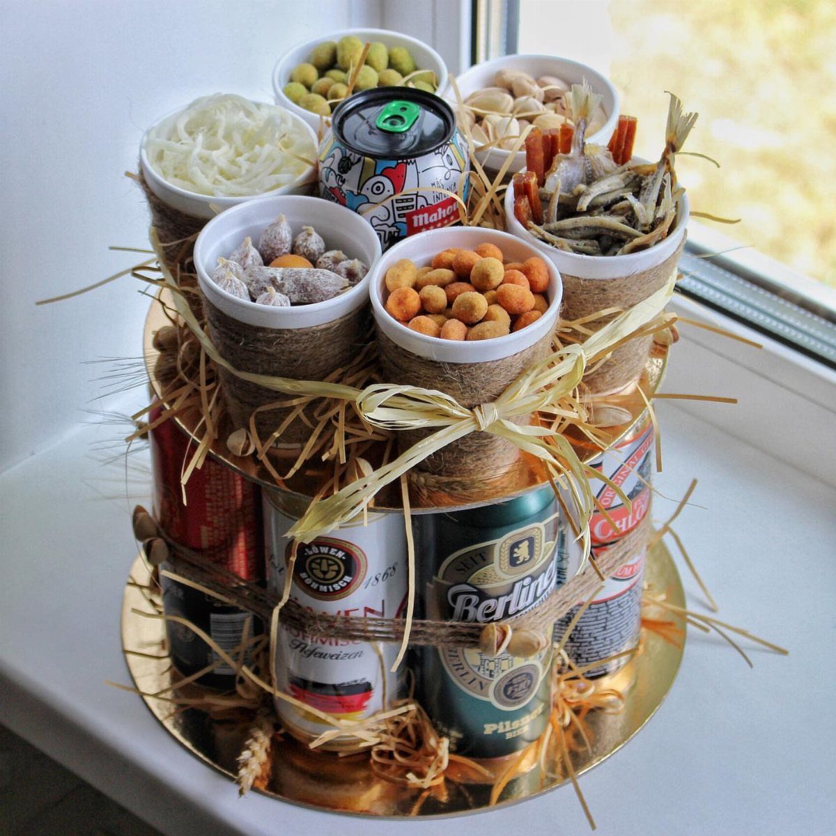 Beer can cake topped with snack bowls, wrapped in twine and straw.