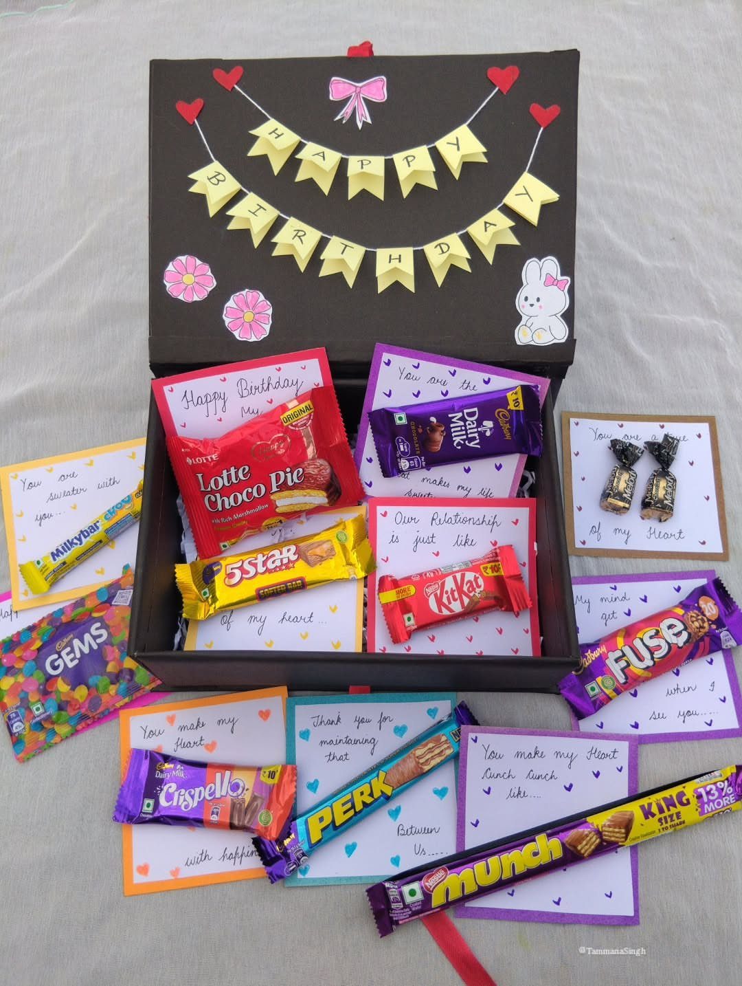 Black birthday gift box filled with assorted chocolates and handwritten love notes.